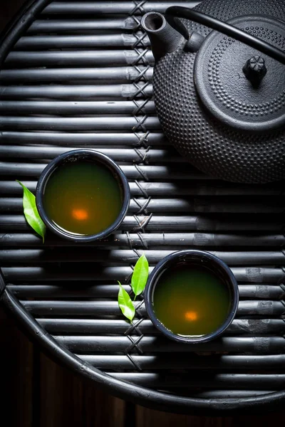 Вид на зеленый чай с чайником на черном столе — стоковое фото