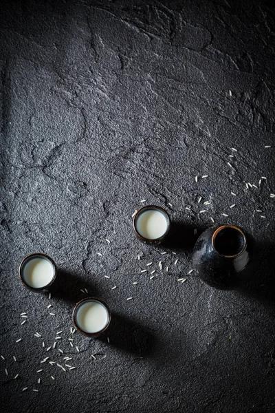 Saké blanc en céramique noire sur rocher noir — Photo