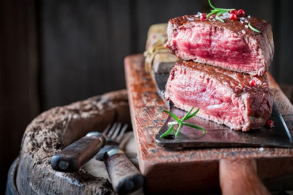 Closeup of steak with rosemary and salt on wooden plank — Stock Photo, Image