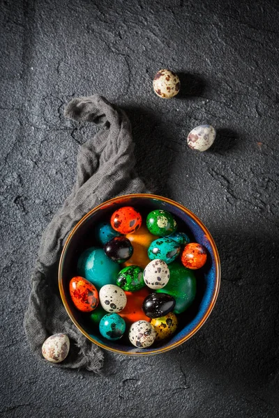 Colorful Easter eggs in blue bowl on black table — Stock Photo, Image