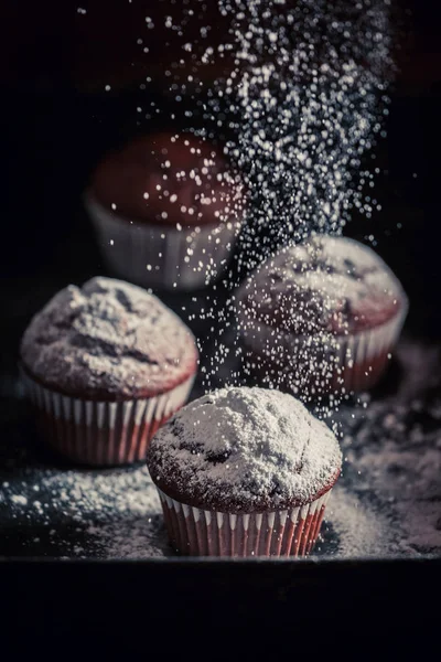 Falling powdered sugar on brown chocolate muffin — Stock Photo, Image