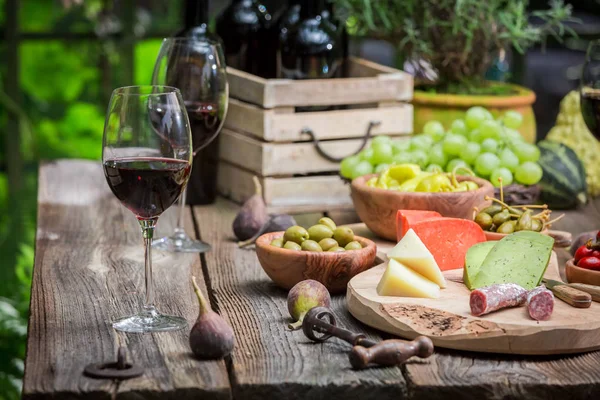 Trädgårdsbord med ost, rött vin på kvällen — Stockfoto