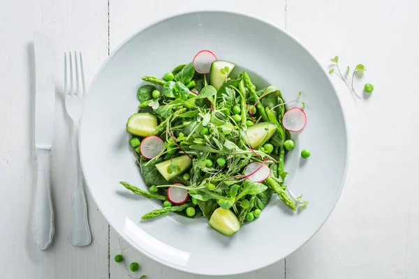 Вегетарианский салат со шпинатом, редиской и спаржей на белом столе — стоковое фото
