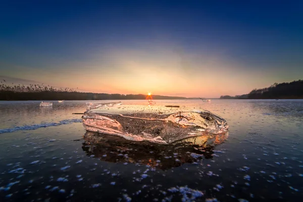 Холодный кусок льда на замёрзшем озере на закате — стоковое фото