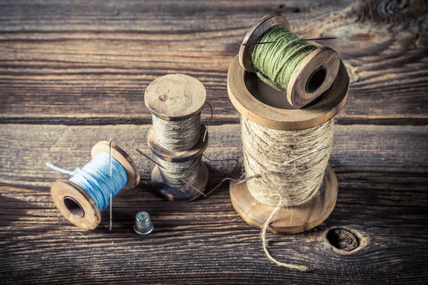 Naalden en draden in kleermaker workshop over houten achtergrond — Stockfoto
