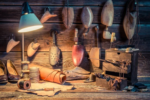 Инструменты, обувь и кожа на рабочем месте обувщика — стоковое фото