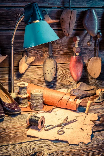 Обувь, инструменты и кожа в старой мастерской сапожника — стоковое фото