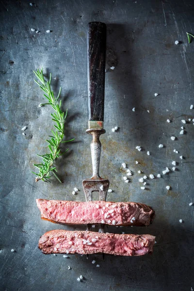 Couper en deux un steak servi avec du sel et du romarin — Photo