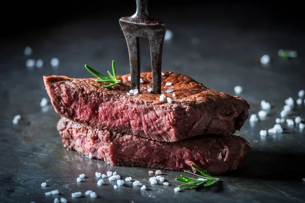 Closeup of medium rare steak with salt and herbs — Stock Photo, Image