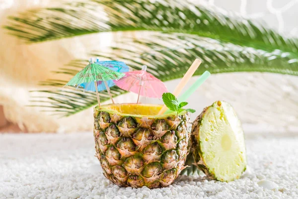 Söt dricka i ananas med cocktail parasoller på vita stenar — Stockfoto