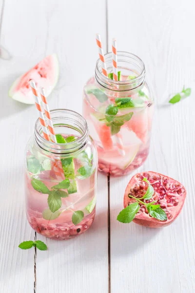Acqua in vaso con frutta e menta sul tavolo bianco — Foto Stock