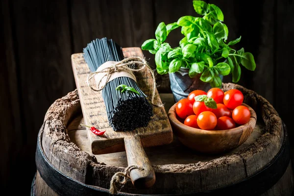 Esparguete preto com ervas e tomates em barril de madeira — Fotografia de Stock