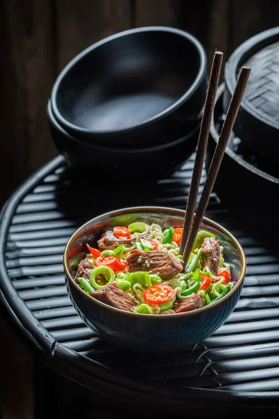 Mie Asia panas dengan sayuran dan daging sapi di atas meja hitam — Stok Foto