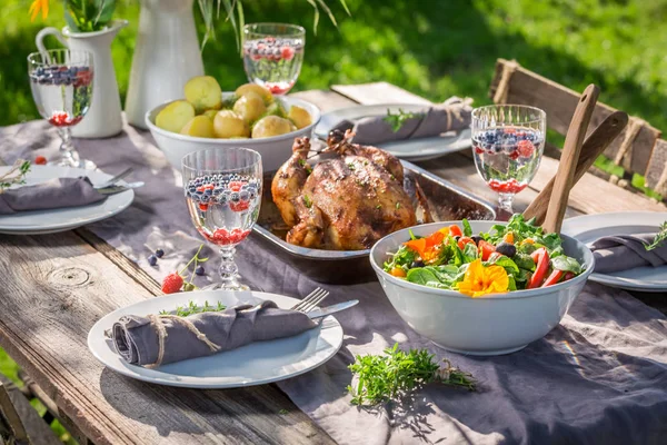 Tabell i trädgård med sallad och kyckling som serveras i sommar — Stockfoto