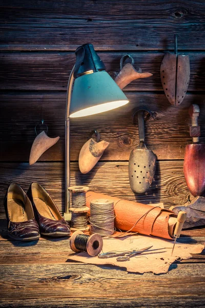 Ročník ševcovské dílny s obuví a tkanicemi na dřevěném stole — Stock fotografie