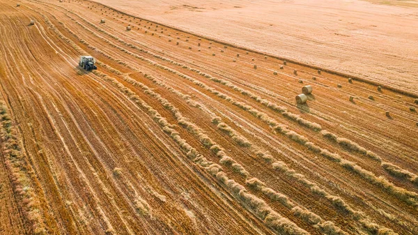 Sahasında yuvarlak saman olan traktör, hava manzaralı. — Stok fotoğraf