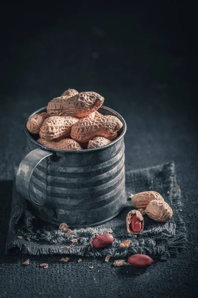 Grupo de cacahuetes con en vieja taza de metal rústico — Foto de Stock