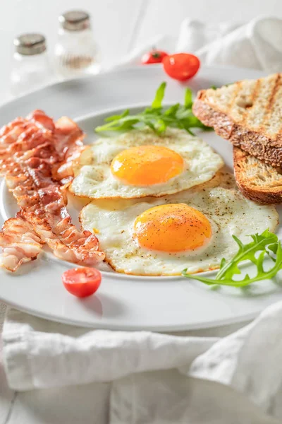 Kotitekoinen aamiainen paahtoleivällä, pekonilla, munilla ja tomaateilla — kuvapankkivalokuva