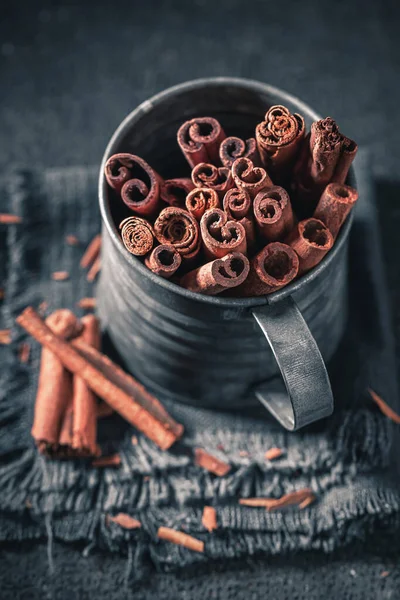 Bastoncini di cannella in vecchia tazza su uno sfondo scuro — Foto Stock