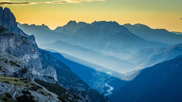 Utsikt mot dimmig dal i Dolomiterna vid soluppgången — Stockfoto