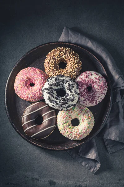 Donuts com decorações coloridas na mesa escura — Fotografia de Stock