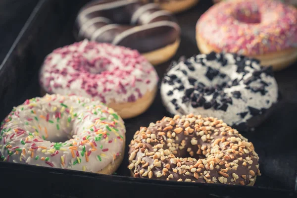 Homemade donuts with different sprinkles in baking tray — Stock Photo, Image