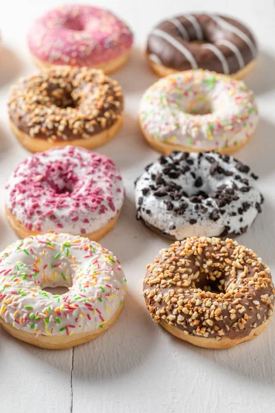 Fechar de rosquinhas com coberturas na mesa branca — Fotografia de Stock