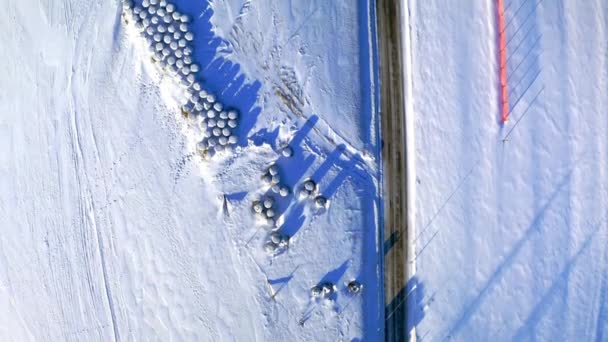 Hay balls on field by road in winter, aerial view — 비디오