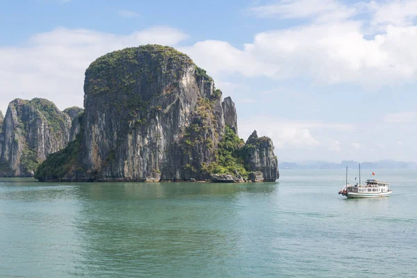 Un pequeño barco en la bahía de Halong junto a una roca — Foto de Stock