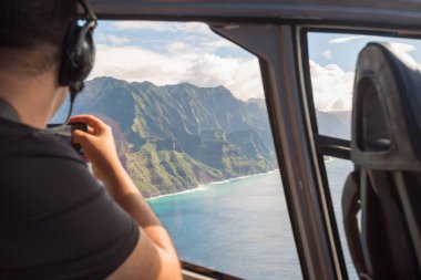 Napali coast from a helicopter with a tourist taking pictures clipart