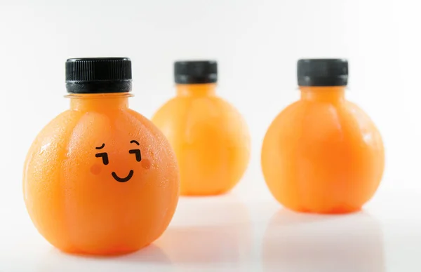 Pomerančová šťáva v plastové kulové láhve s emocionální tváří. Izolované na bílém pozadí — Stock fotografie