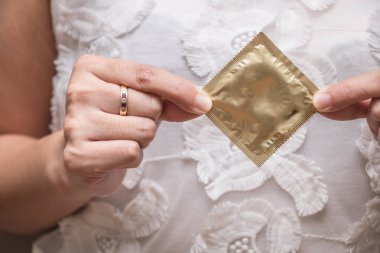 Kadın tutuyor bir prezervatif altın rengi, güvenli seks kavramı