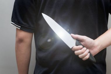 Bir genç adam el, holding bıçak onun sırt ve saldırı için bir kadın için bekleyen arkasında closeup, genel kavram-in tehlike, stres, unfulfillment, risk.