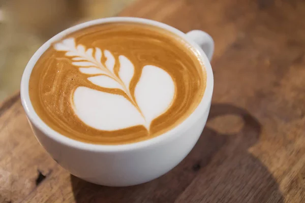 Bovenaanzicht van warme koffie cappuccino latte art in witte keramische cup op houten plaat — Stockfoto