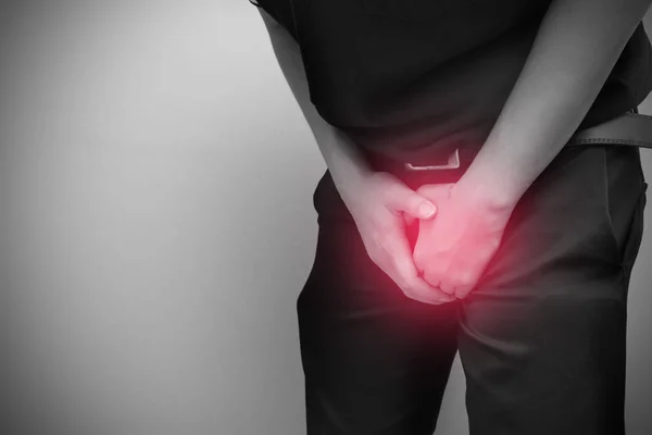 Genital bölgesini tutan genç adam ağrıya, prostat kanserine, erken boşalmaya, doğurganlığa, idrar sorununa neden olur.