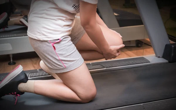 Asyalı kadın runner makine treadmill fitness salonunda spor yaralanma var