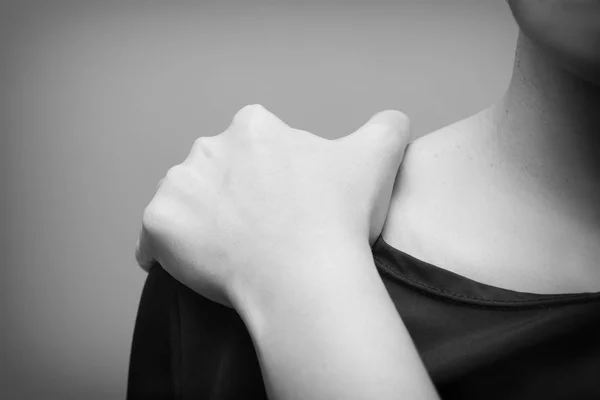 Młoda kobieta cierpi na ból barku, ból w organizmie człowieka na szarym tle-czarno-białe — Zdjęcie stockowe