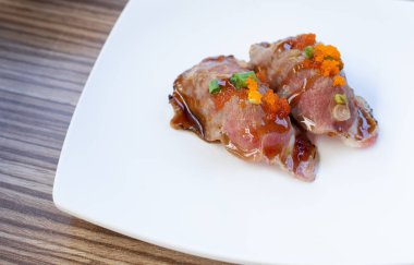 Biftekli suşi beyaz tabakta servis ediliyor. Japon geleneksel yemekleri