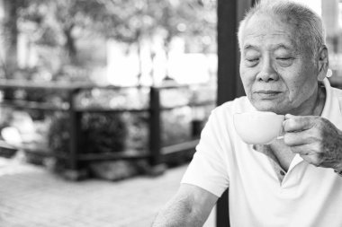 Dışarıda kahve içen yaşlı bir adam. Sağlıklı son sınıf konsepti. Siyah ve beyaz ton