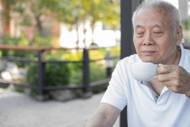 Dışarıda kahve içen yaşlı bir adam. Sağlıklı son sınıf konsepti