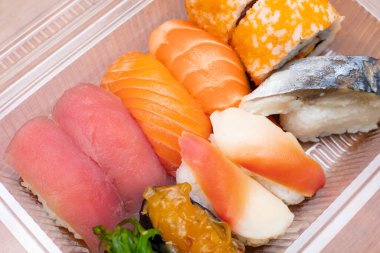 Teslimat için plastik kutuda çeşitli suşiler var. Yemek teslimatı konsepti. Japon geleneksel yemekleri