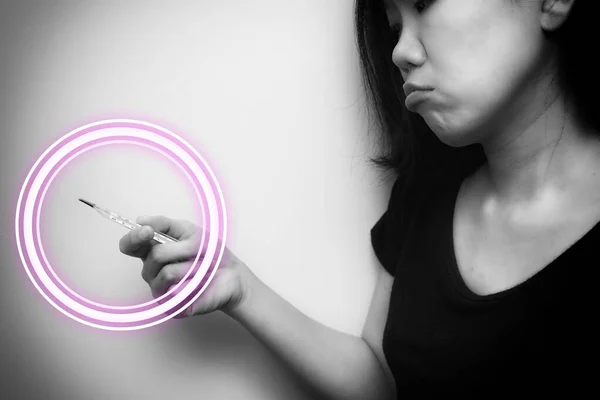 Asian woman looking at  clinical thermometer on her hand for checking temperature. With anxiety mood. Black and white tone with circle wave on thermometer. Diagnosis and test COVID-19.