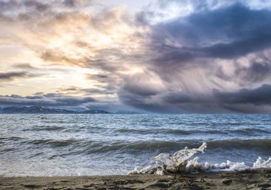 Kumlu bir kumsalda, renkli bir günbatımı gökyüzü ile dalgalar sıçradı..