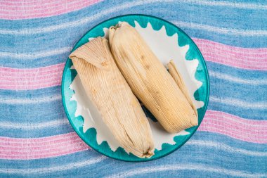 Tatlı Tamale, mısır hamurundan yapılmış kuru üzüm ve çilek ya da ananas aromalı, mısır yaprağıyla sarılmış.