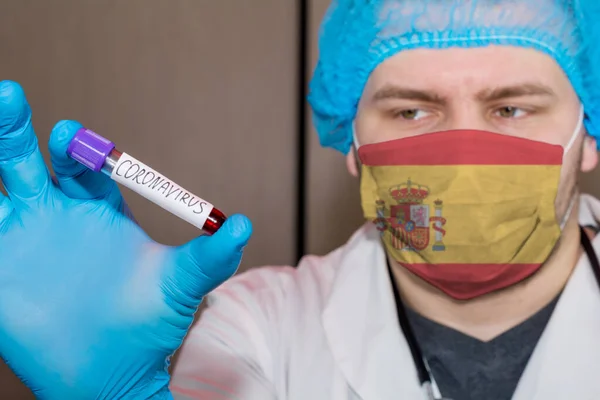 Doctor wearing mask with flag Spain holding a blood test for the Coronavirus