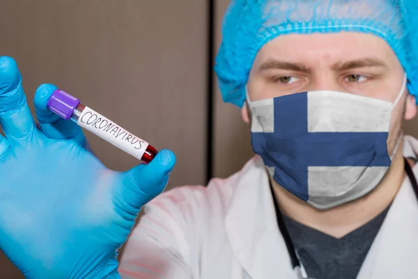 Doctor wearing mask with flag Finland holding a blood test for the Coronavirus