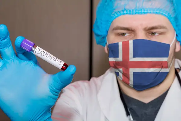 Doctor wearing mask with flag Iceland holding a blood test for the Coronavirus