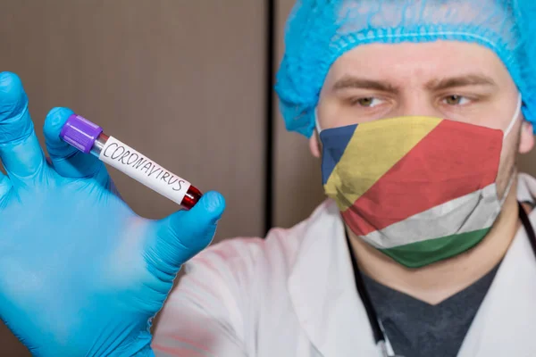Doctor wearing mask with flag Seychelles holding a blood test for Coronavirus
