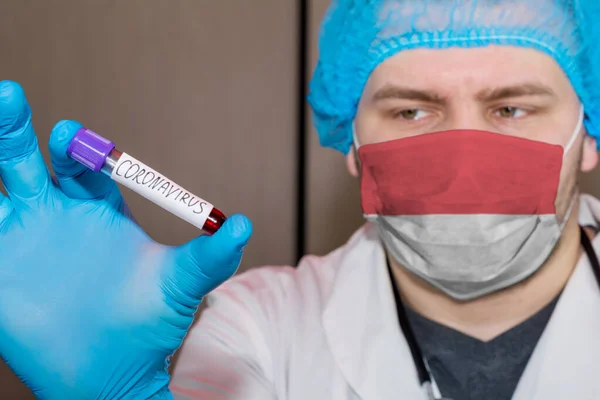 Doctor wearing mask with flag Monaco holding a blood test for the Coronavirus