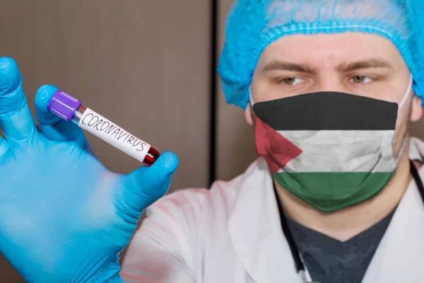 Doctor wearing mask with flag Palestine holding a blood test for the Coronavirus
